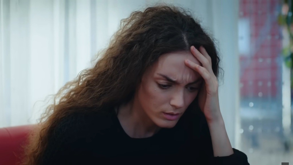 Nana budzi się, zdezorientowana, pocierając czoło dłonią.