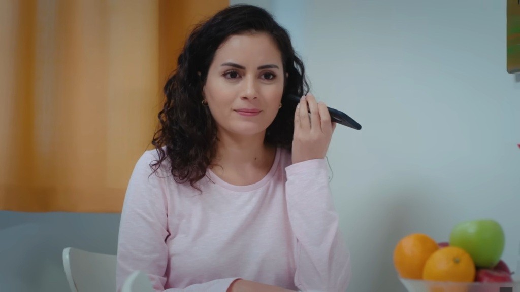 Aynur odsłuchuje wiadomość od prokuratora. Na jej twarzy maluje się delikatny uśmiech.