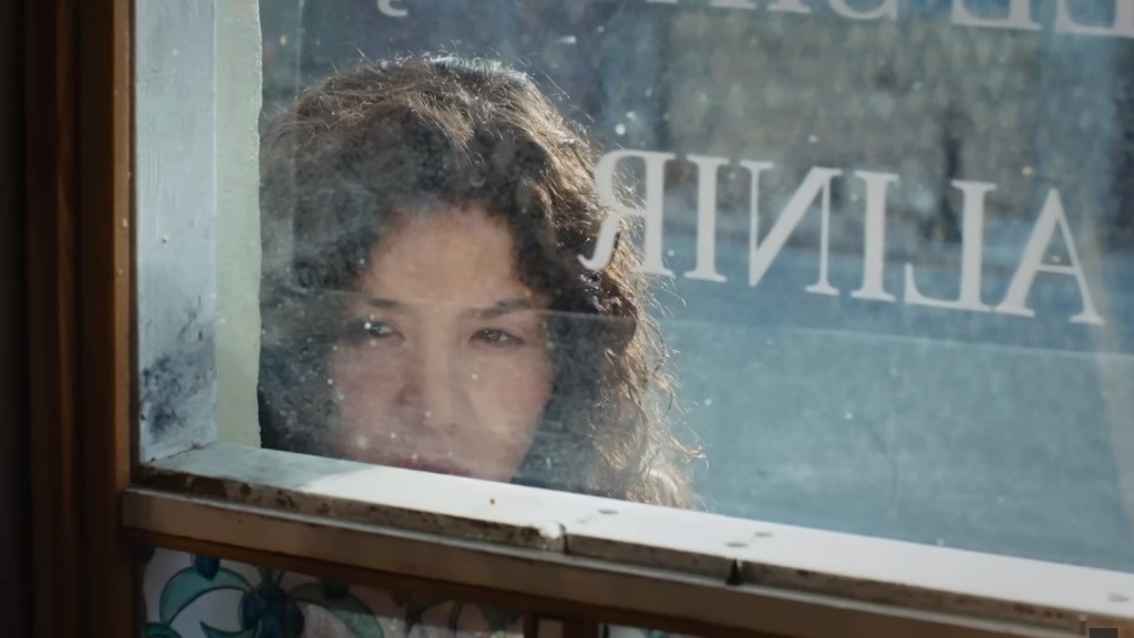 Cansel zagląda przez okno do środka warsztatu.