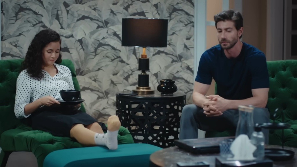 Aynur ma obandażowaną kostkę. Obok siedzi Sinan.