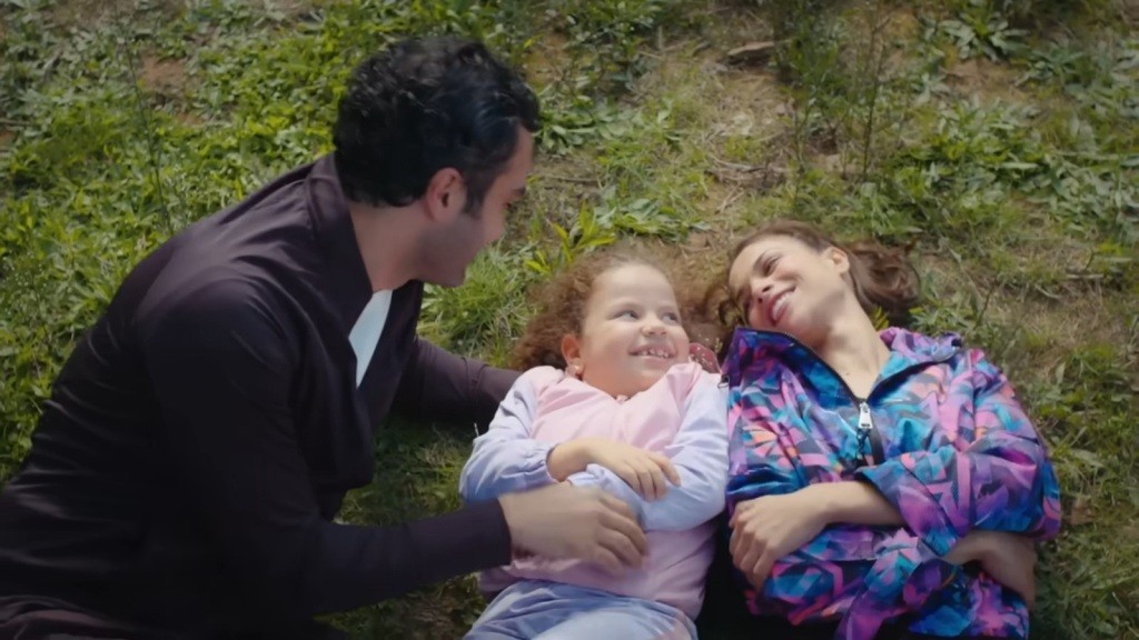 Ferit, Doga i Ayse leżą na trawie.