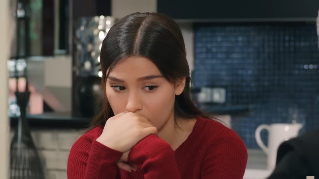 Zeynep siedzi przy stole, opierając zasmuconą twarz na dłoniach.