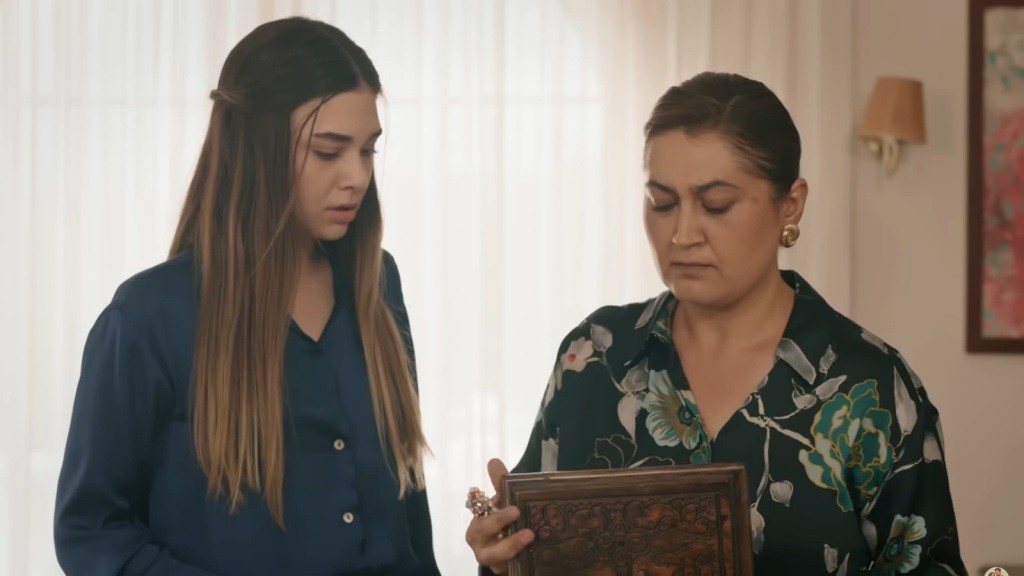 Canan trzyma pudełko z naszyjnikiem. Obok niej stoi Asu.