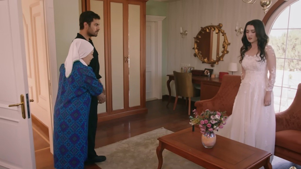 Zumrut wprowadza Halila do swojego pokoju, gdzie stoi Zeynep ubrana w suknię ślubną.