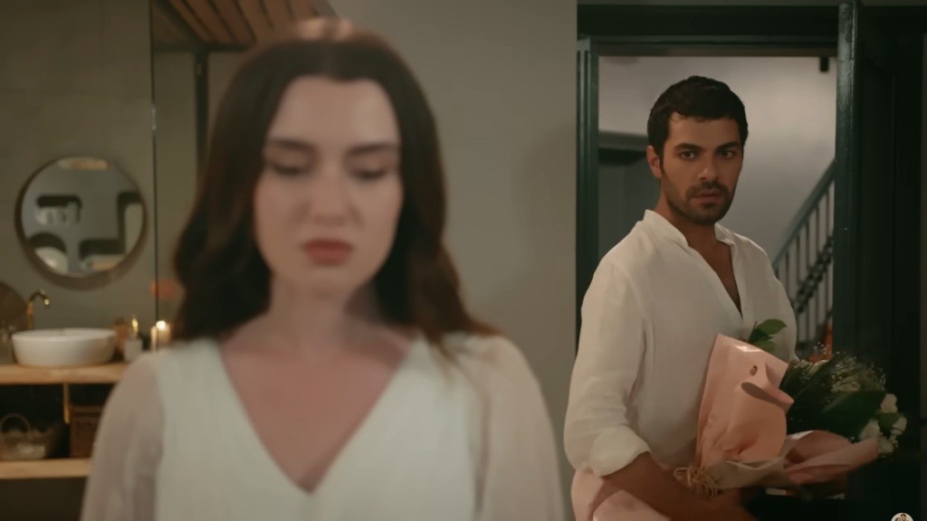Halil wraca do pokoju hotelowego z kwiatami. Zeynep jest odwrócona do niego plecami. Wydaje się przygnębiona.