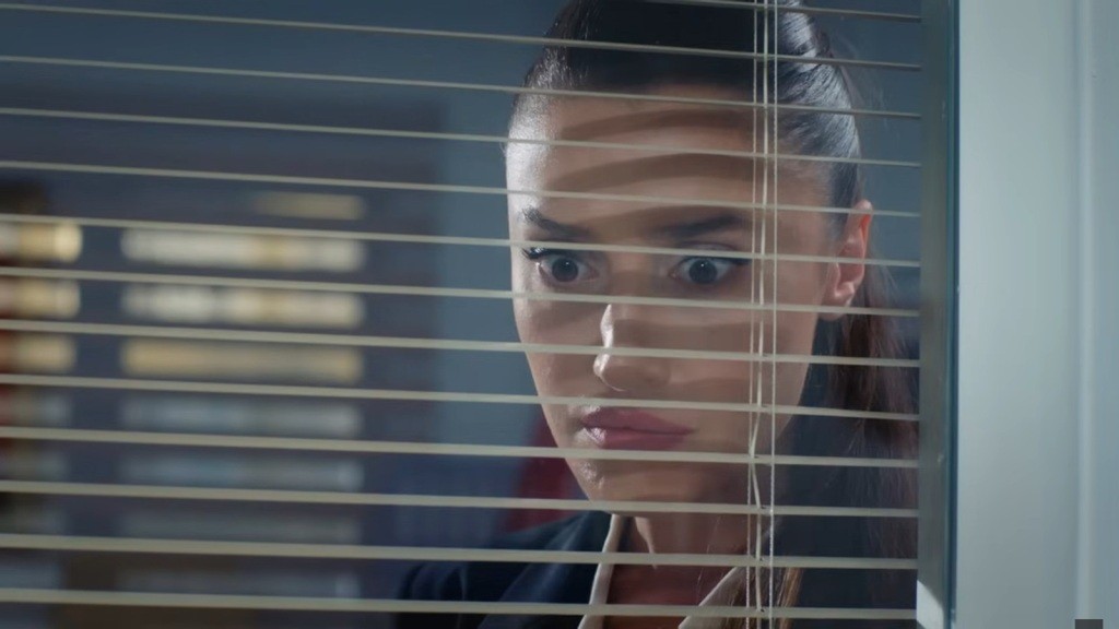 Derya patrzy przez okno z wyrazem szoku na twarzy.