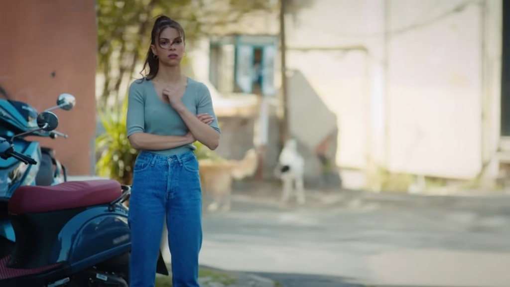 Ayse stoi na zewnątrz obok zaparkowanego skutera.