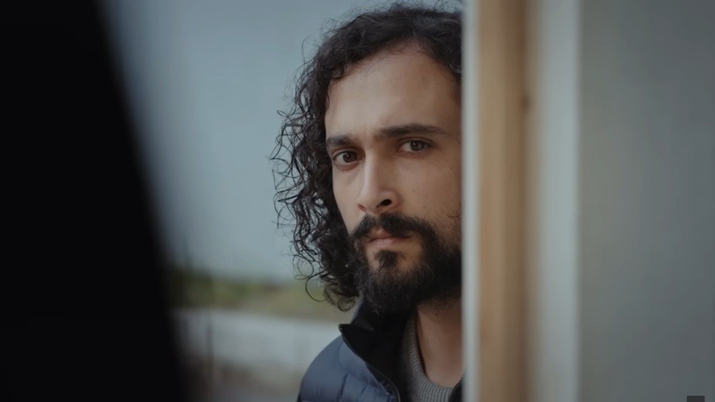 Semih prowadzi obserwację zza drzwi.