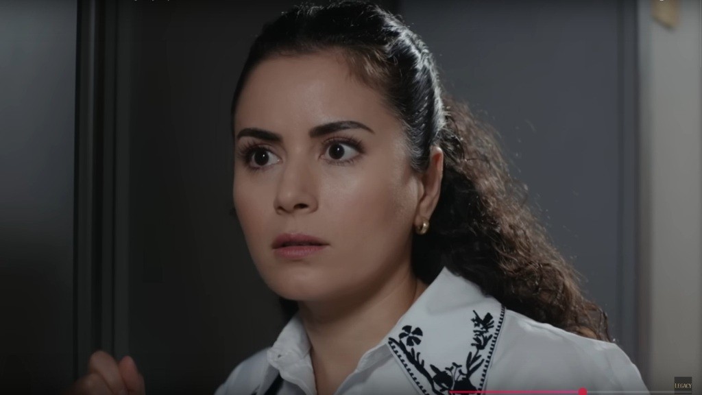 Aynur zastyga nieruchomo, z wyrazem szoku na twarzy.