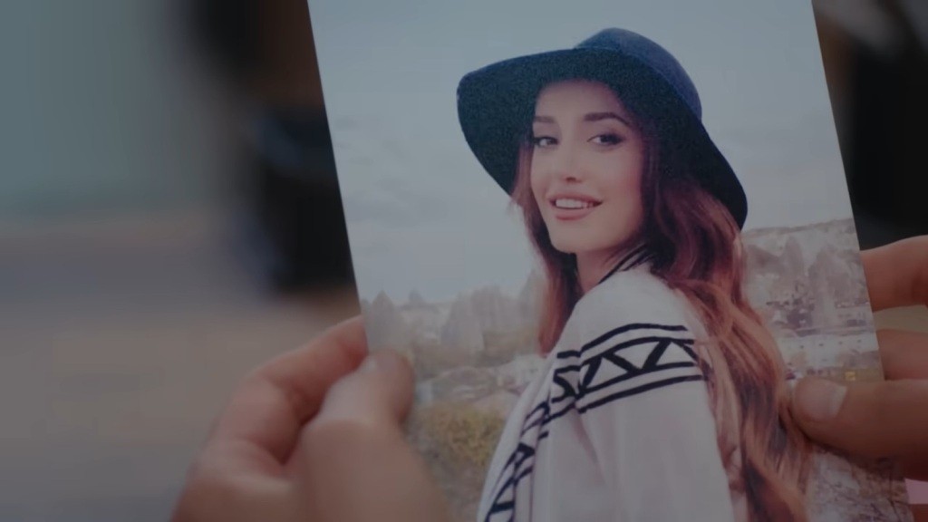 Zdjęcie Deryi w rękach Ayse. Na fotografii Derya ma rozpuszczone włosy i kapelusz na głowie.