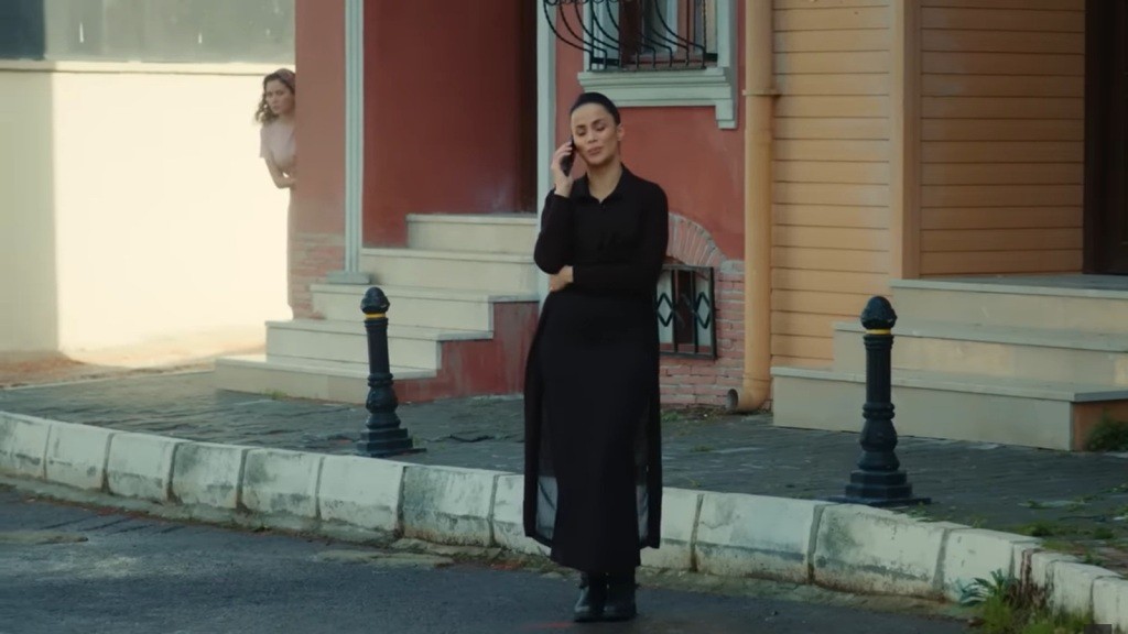 Aynur wygląda zza winkla, przysłuchując rozmawiającej przez telefon Lerzan.