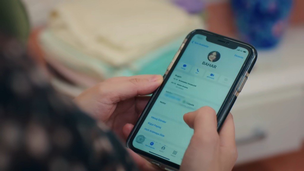 Zbliżenie na ekran telefonu Cavidan. Wyświetlony jest na nim kontakt do jej córki, Bahar.