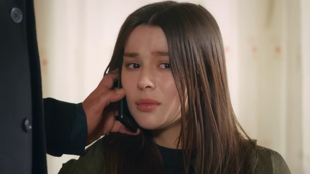 Zbliżenie na twarz przerażonej Zeynep. Ma przyłożony telefon do policzka.