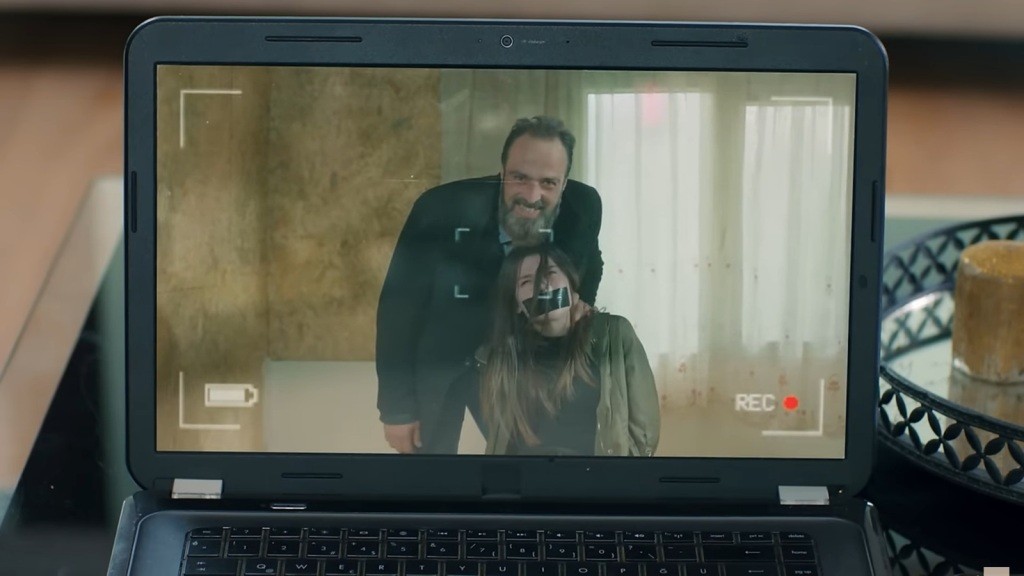 Zbliżenie na ekran laptopa, na którym widać porywacza, trzymającego związaną i zakneblowaną Zeynep.
