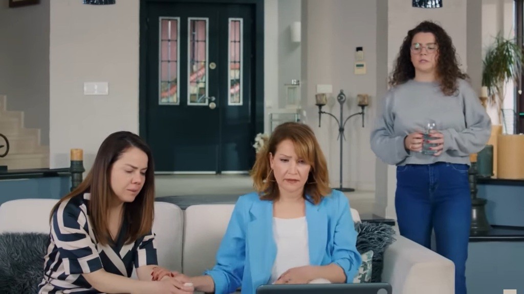 Gonul i Feraye siedzą na kanapie przed laptopem. Obok Melis chodzi nerwowo.