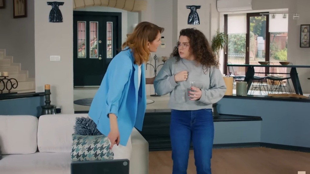 Feraye chwyta Melis za ramię, drugą ręką wskazując na ekran laptopa.