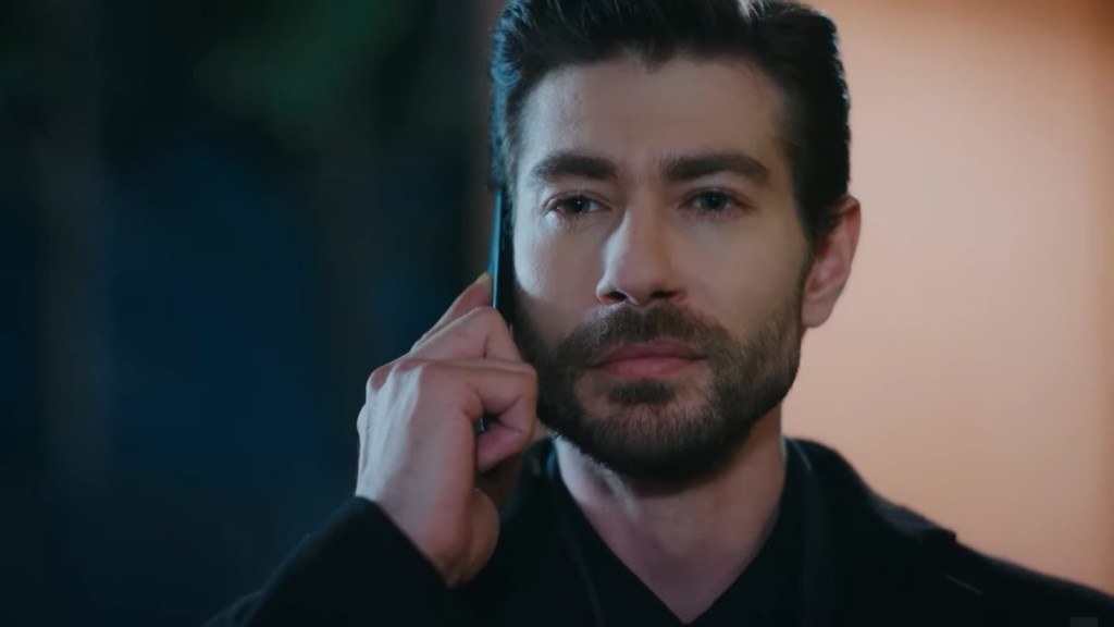 Sinan rozmawia przez telefon, a na jego twarzy maluje się wyraz determinacji.
