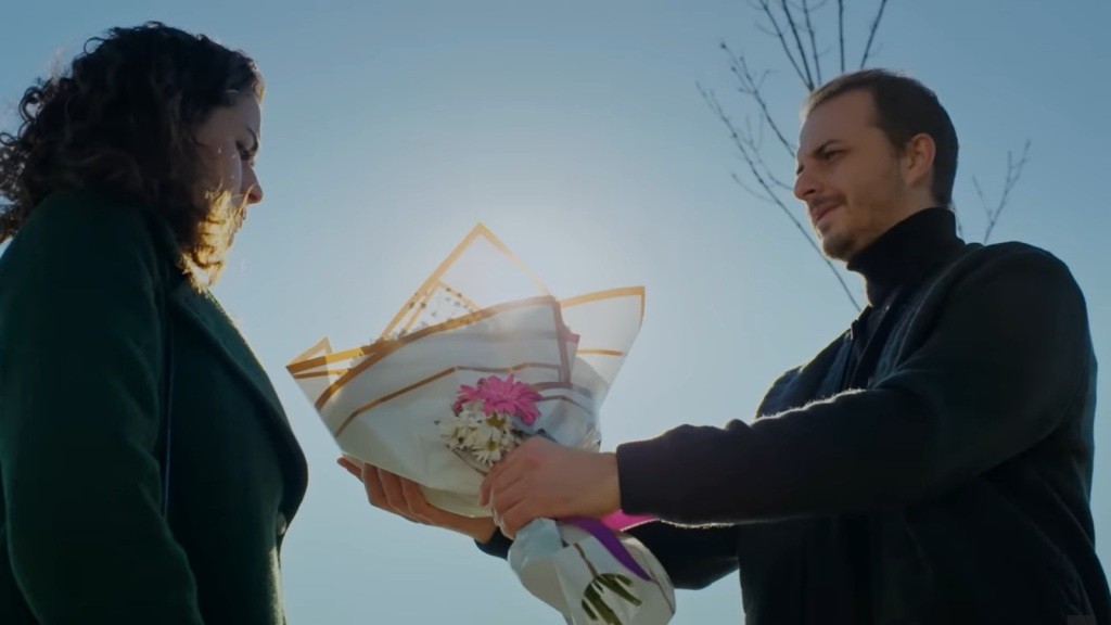 Kivanc wręcza Aynur bukiet kwiatów.