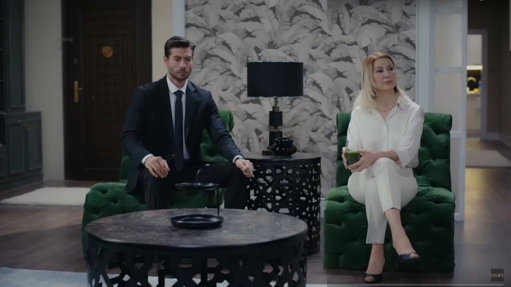 Sinan i jego matka siedzą na fotelach w salonie. Isil trzyma w rękach szklankę zielonego smoothie.