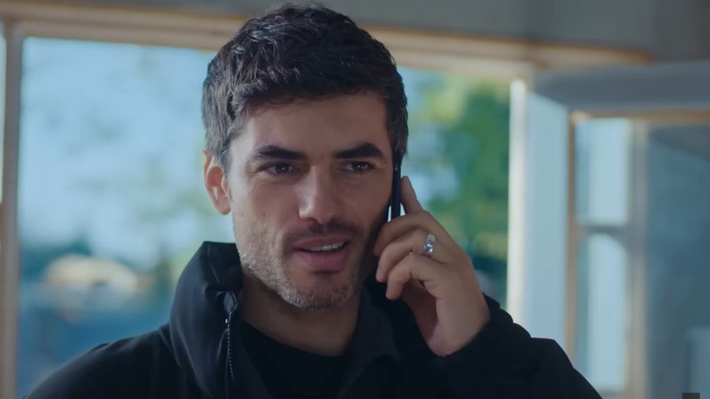 Poyraz rozmawia przez telefon z uśmiechem na twarzy.