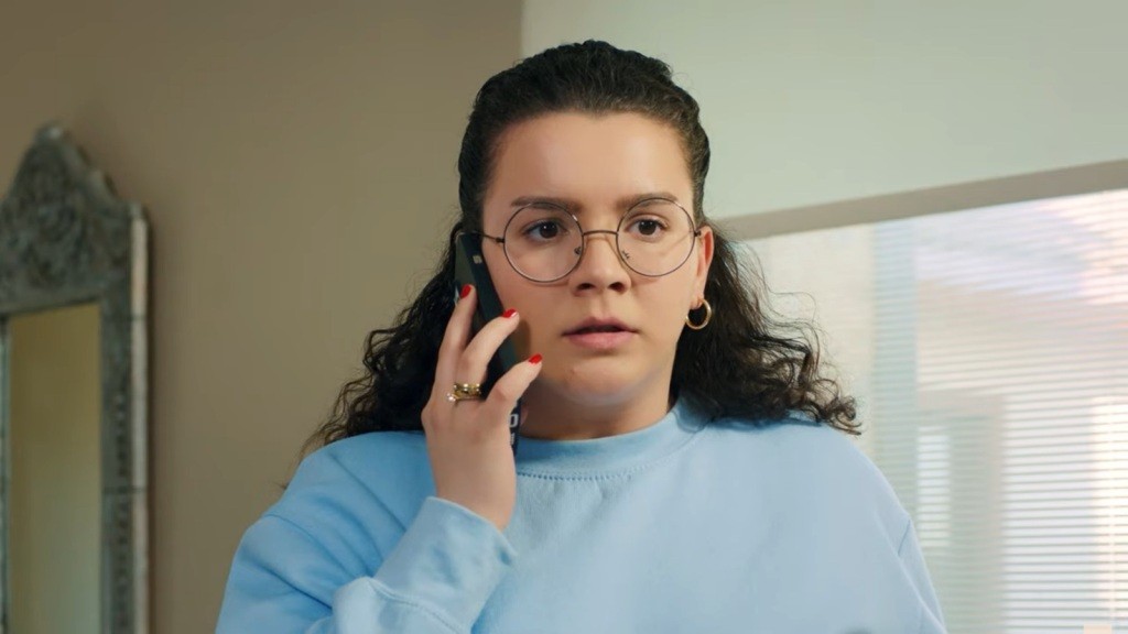 Melis trzyma telefon przy uchu, a jej twarz zdradza głębokie zdruzgotanie.