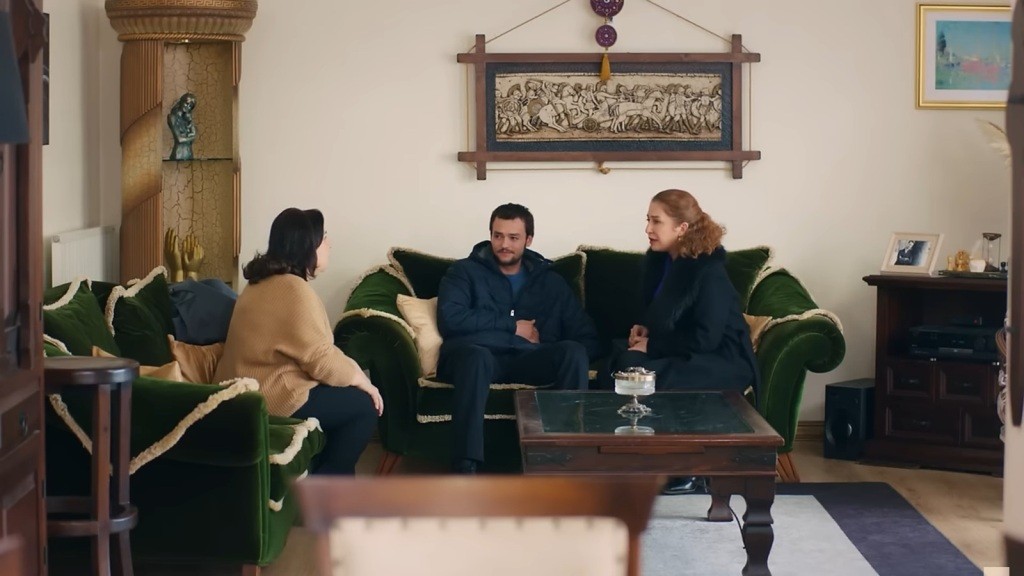 Alper siedzi na kanapie w domu Kuzeya. Hulya i Naciye są obok niego.
