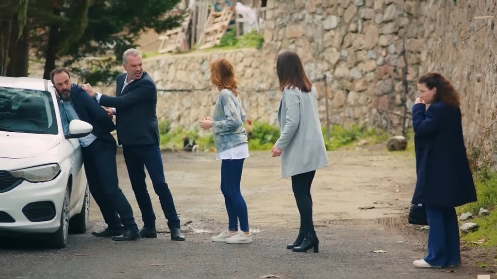 Bulent dociska Ragipa do drzwi samochodu. Feraye, Yildiz i Melis stoją obok.