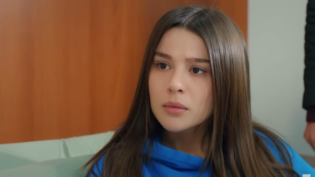 Zeynep leży na szpitalnym łóżku, a jej wyraz twarzy zdradza zarówno zaintrygowanie, jak i zaniepokojenie.
