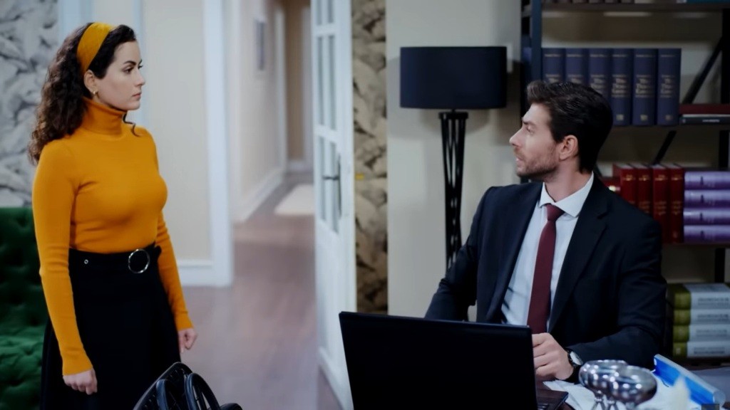 Aynur podchodzi do pracującego przy stole Sinana.