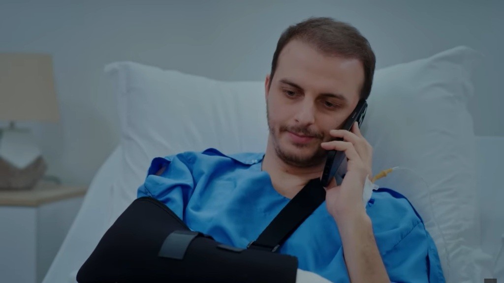 Kivanc rozmawia przez telefon, leżąc na szpitalnym łóżku.