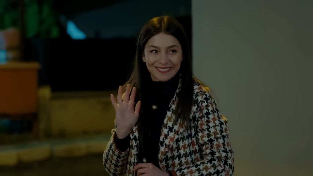 Sibel macha ręką i uśmiecha się zalotnie.