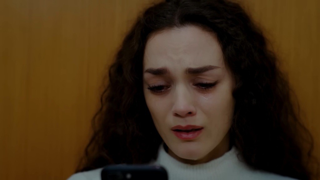 Zapłakana Nana wpatruje się w swój telefon.