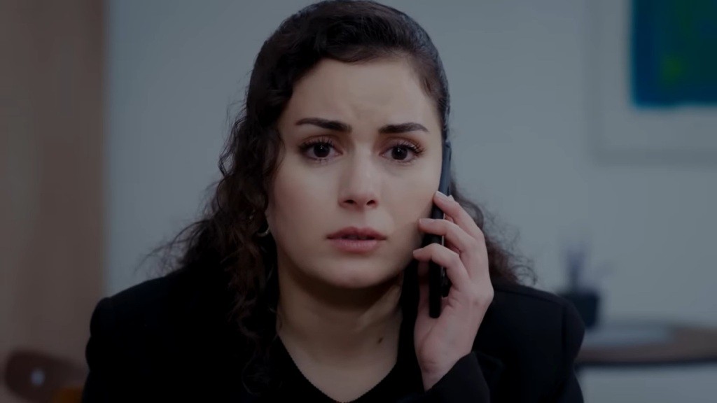 Aynur rozmawia przez telefon. Jej twarz wyraża przejęcie.