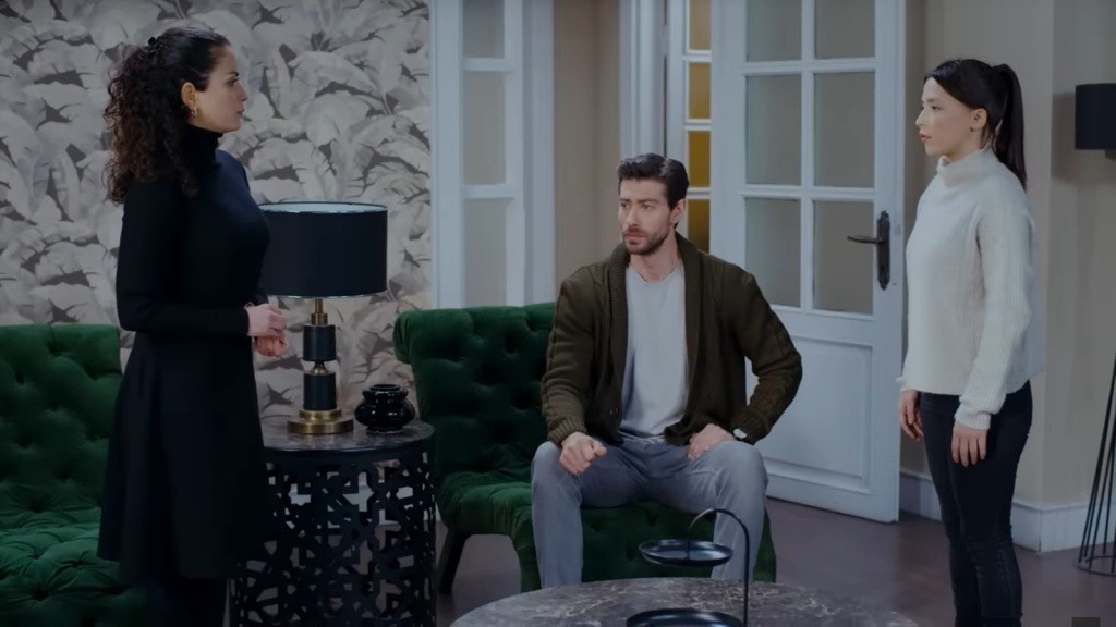 Aynur stoi naprzeciwko Ezgi. Sinan siedzi w fotelu między nimi.