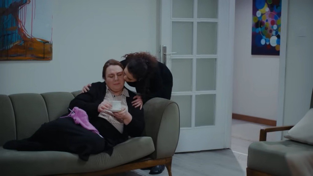Aynur pochyla się nad leżącą na sofie Adalet i całuje ją.