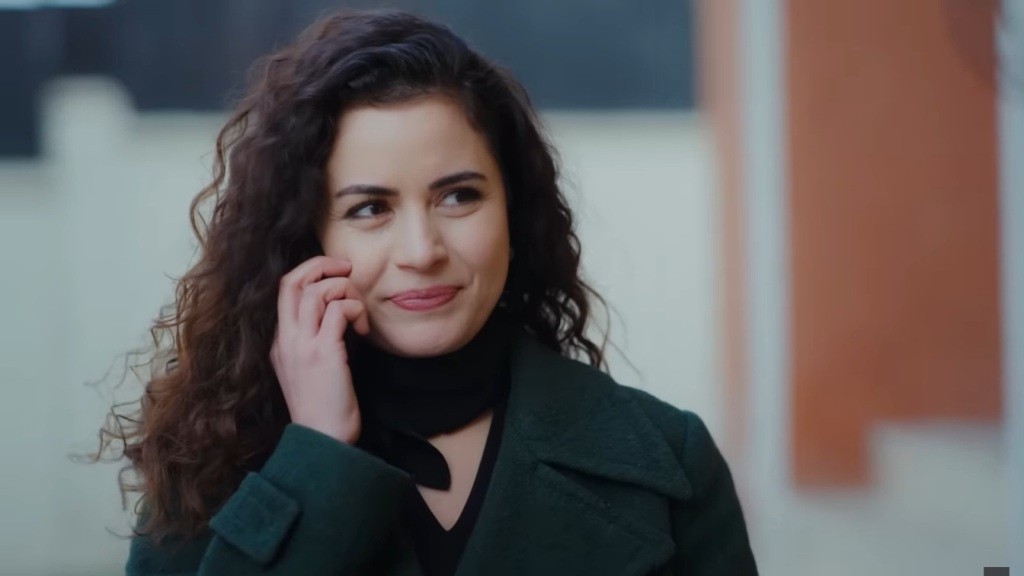 Aynur rozmawia przez telefon. Na jej twarzy maluje się pogodny uśmiech.