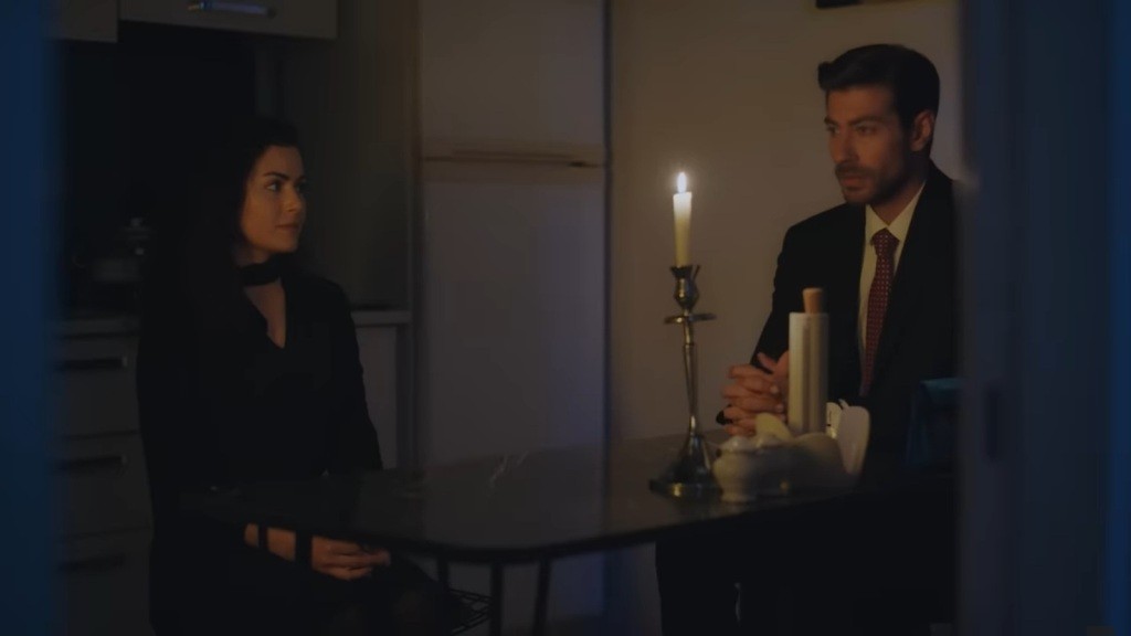Aynur i Sinan siedzą przy stoliku w kuchni. Pomieszczenie oświetlone jest tylko światłem świecy.