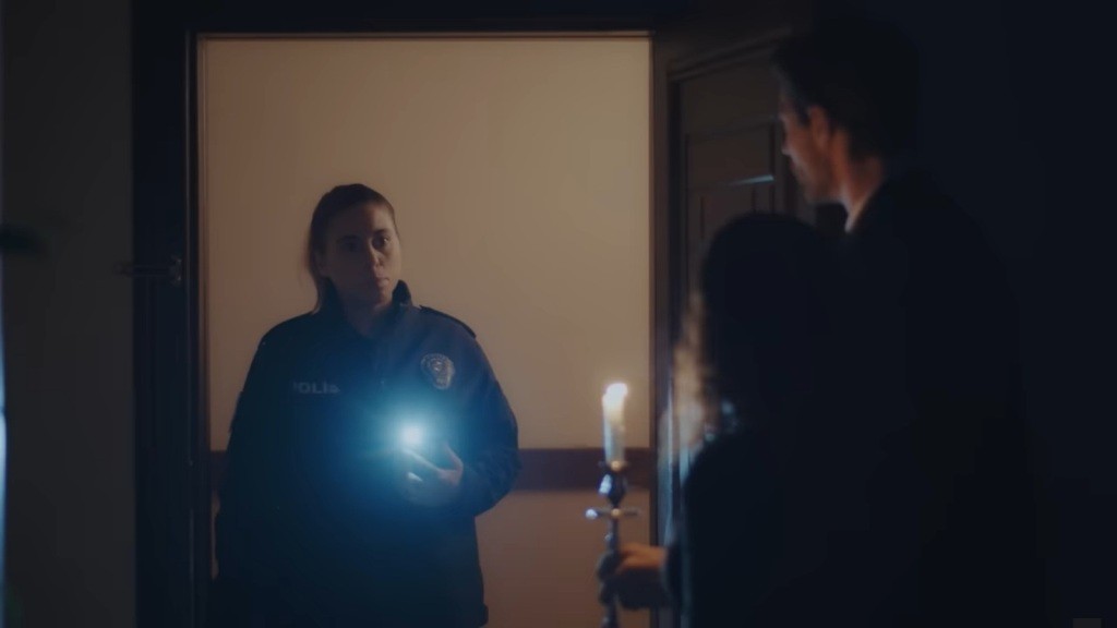 Przed drzwiami domu Sinana stoi policjantka. Aynur i Sinan stoją w przedpokoju.