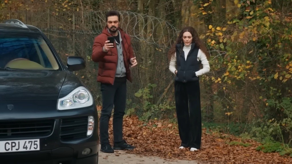 Yaman i Nana stoją obok samochodu. Mężczyzna trzyma telefon w ręku, zapewne szukając sygnału.