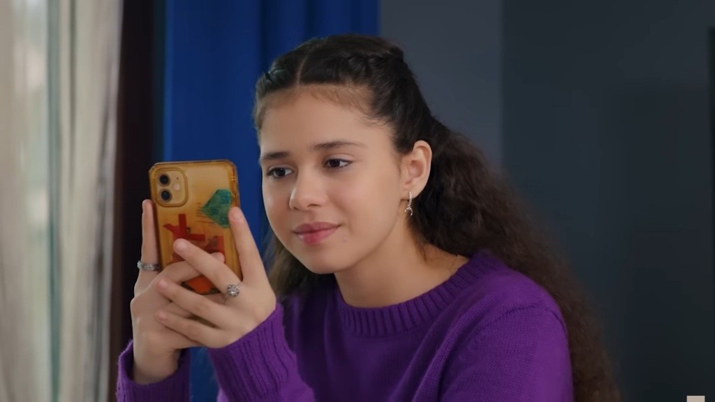 Melodi trzyma telefon w rękach, robiąc zdjęcie.