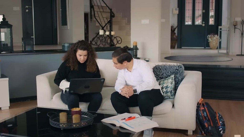 Melis trzyma laptopa na kolanach. Obok siedzi Yigit.