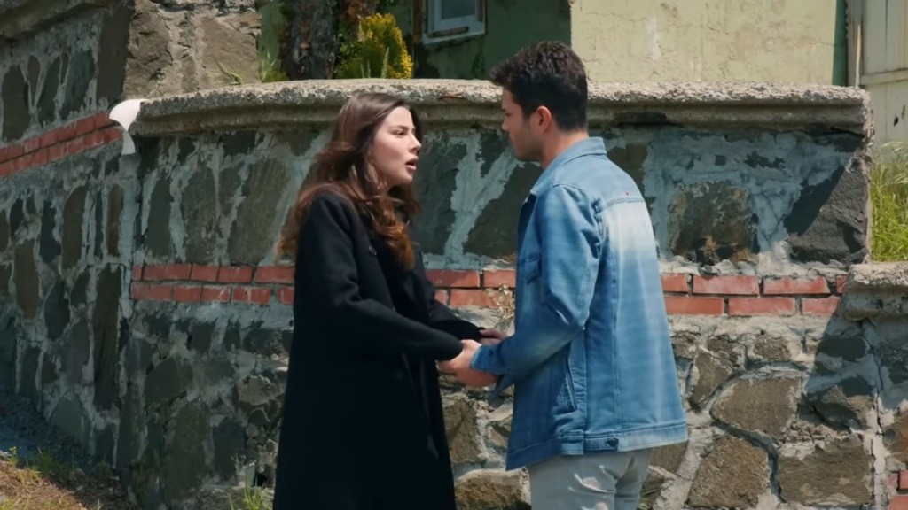 Ege trzy Zeynep za ręce, stojąc naprzeciwko niej na zewnątrz.