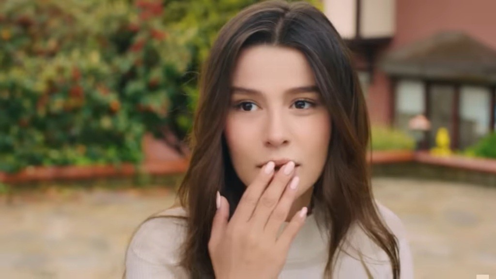 Oniemiała Zeynep dotyka dłonią swoich ust.