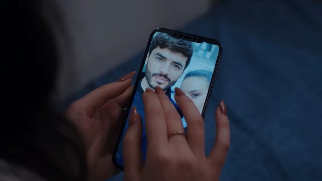 Zdjęcie Poyraza sprzed kilku lat na telefonie Pelin. Kobieta dotyka palcami ekranu, jakby chciała dotknąć prawdziwego Poyraza.
