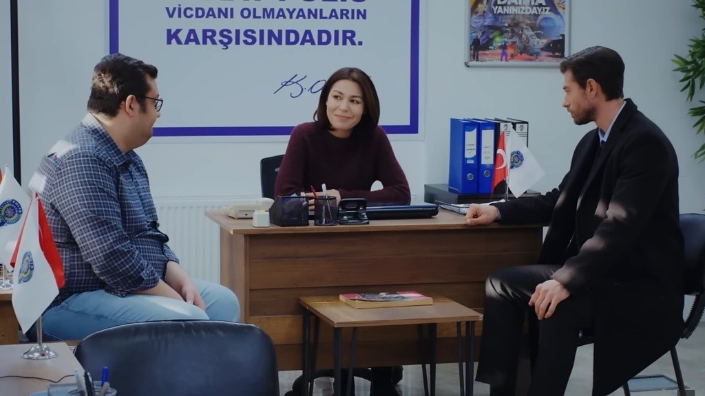 Ibrahim, Kara i Sinan rozmawiają na komisariacie. Kara uśmiecha się.