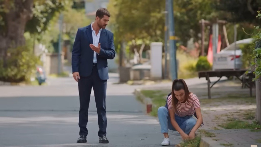 Zeynep kuca przy krawężniku, szukając naszyjnika. Cihan stoi obok.