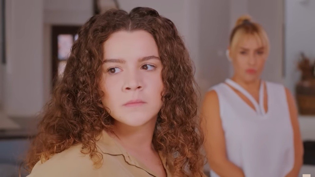 Melis odwraca głowę z niezadowoloną miną. Tuż za nią stoi Belkis.