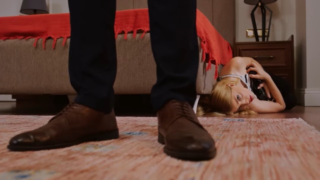 Seda chowa się za łóżkiem. Zadziera głowę, patrząc na buty stojącego tuż obok niej Egego.