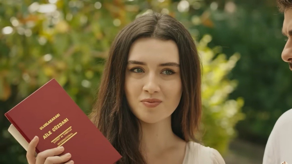 Zeynep z uśmiechem na twarzy prezentuje akt ślubu.