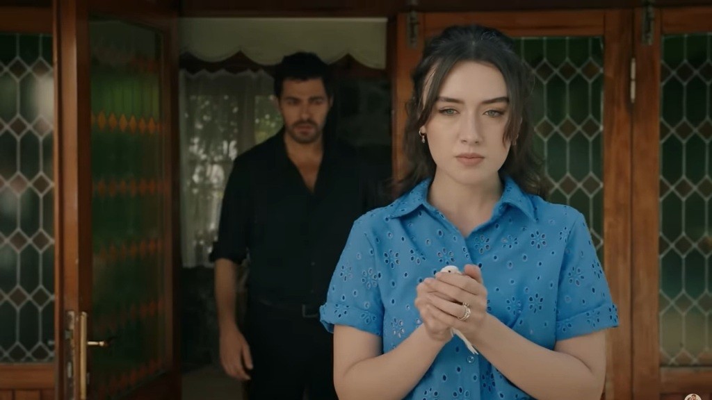 Zeynep trzyma w dłoniach białego kanarka. Za jej plecami stoi Halil.